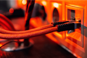 Braided red Ethernet cables plugged into network ports with warm lighting