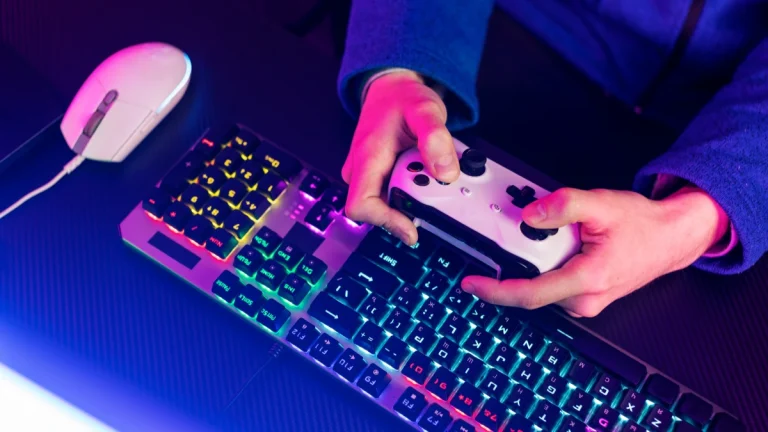 Person holding gaming controller above RGB mechanical keyboard and wired mouse Purpose: Clear and descriptive for accessibility tools and search engines.
