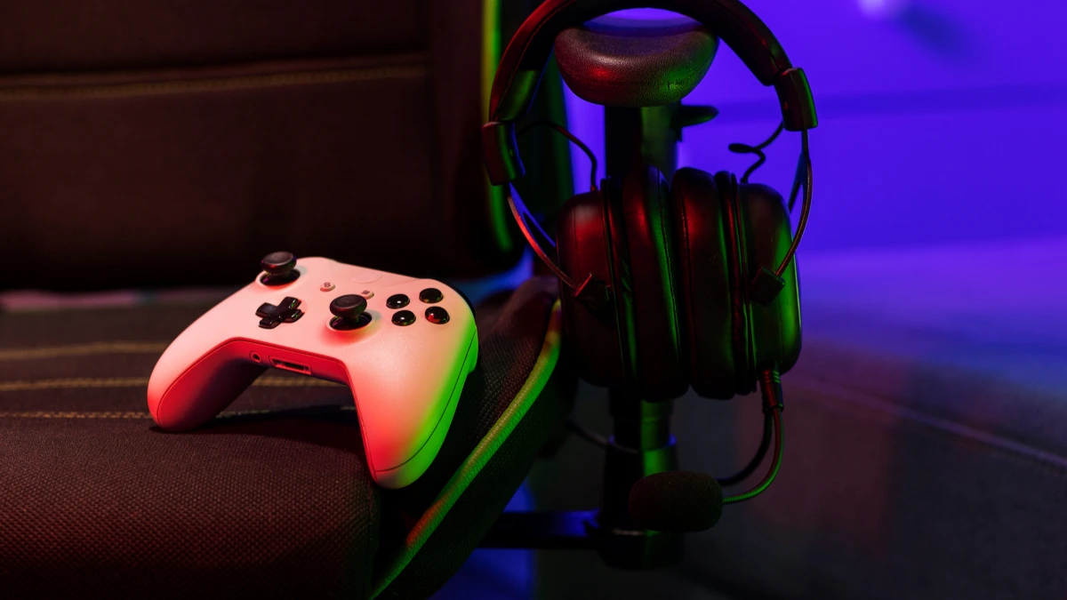 Gaming controller and headset on chair with colorful ambient lighting Purpose: Clear and concise for accessibility tools and search engines.