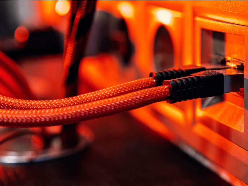 Braided red Ethernet cables plugged into network ports with warm lighting